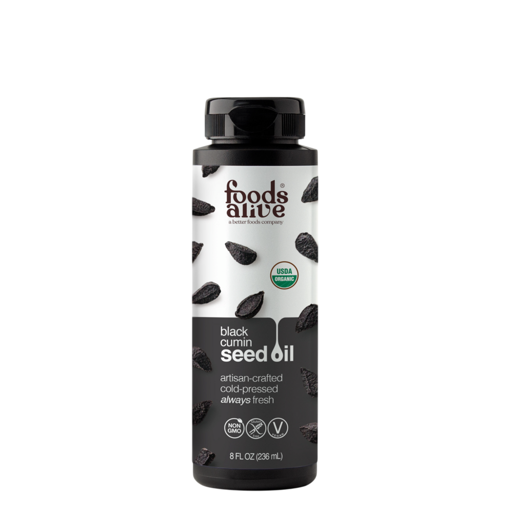 An 8 fl oz bottle of Foods Alive Black Cumin Seed Oil on a solid white background. The bottle is black with a white and black label featuring illustrations of cumin seeds and a USDA Organic seal.